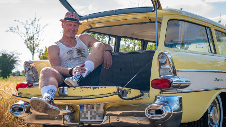 Mann sitzt auf Heckklappe von gelbem Pontiac Oldtimer